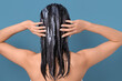 © Pixel-Shot - Asian woman applying hair mask on blue background, back view