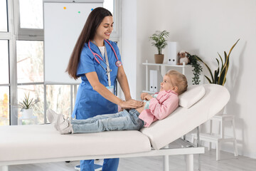 Wall Mural - Female pediatrician examining little girl on couch in clinic