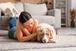 © Pixel-Shot - Young woman lying on floor with cute Australian Shepherd dog in living room