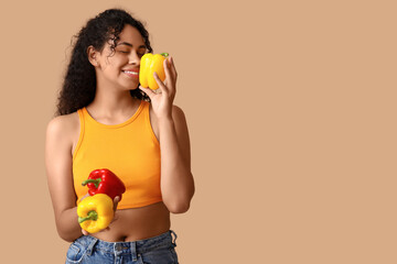 Wall Mural - Young African-American woman with fresh bell peppers on beige background. Independence from Meat Day