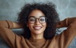 © jiawei - A woman with curly hair and glasses is smiling and sitting on a couch