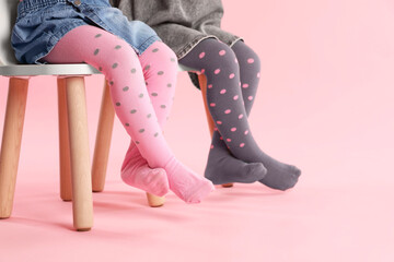 Wall Mural - Kids wearing tights on stool against pink background, closeup. Space for text