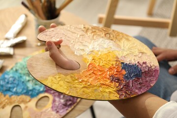 Wall Mural - Man holding wooden palette with paints indoors, closeup