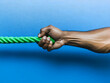 © Siasart Stock - Hand Gripping a Green Rope Against a Blue Background
