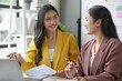© amnaj - Two young businesswomen discussing and working together with financial report in the office