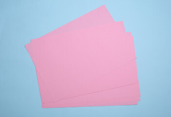 Wall Mural - Pink sheets of paper of A4 size on blue background