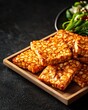 © AImagine Designs - Sustainable alternative plant-based vegan protein and raw food ingredient concept. Delicious tempeh slices served on a wooden platter