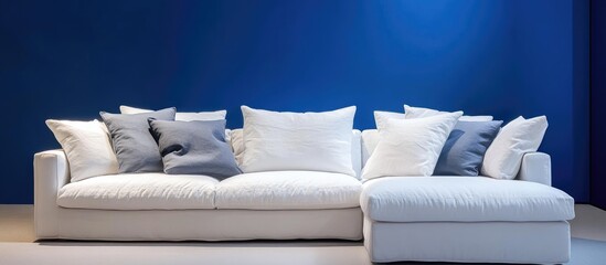 Aufkleber - Modern chic white sofa with decorative pillows against vibrant blue wall, arranged for spacious living room aesthetic, soft lighting enhances elegance.