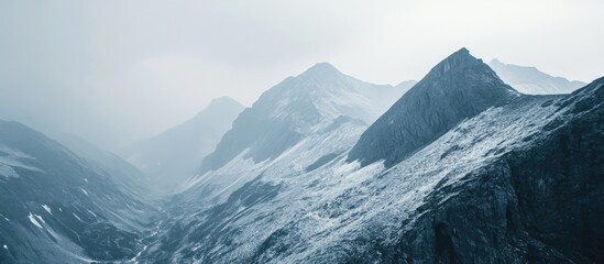 Poster - Serene misty mountain landscape with layered gray and white peaks extending into a foggy sky, ideal for tranquil nature scenes and reflections.