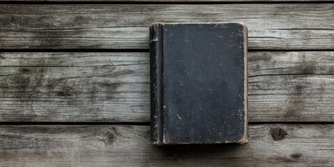 Wall Mural - Vintage black book on aged wooden surface, viewed from above, emphasizing textures in black and white tones, retro aesthetic, rustic style.