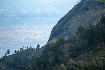 A breathtaking landscape showcasing wind turbines scattered across the valley, framed by the lush hills of Kodaikanal.