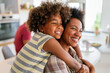 © NDABCREATIVITY - African american woman hugging her smiling teen daughter. Family love single parent child concept