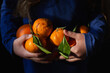 © Cavan Images - Young girl holding pile of tangerines