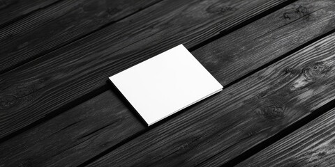 Poster - Minimalist business card mockup displayed on a textured black wooden surface featuring a clean white design with subtle shadows and contrasts.