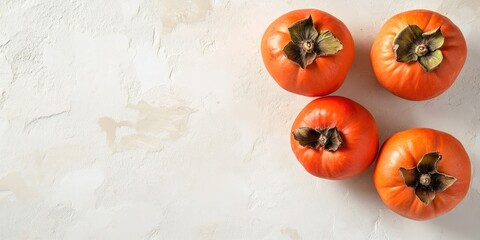 Poster - Fresh vibrant orange persimmons arranged in a cluster on a light textured surface with soft shadows creating a warm autumn feel