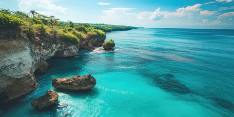 Aufkleber - Serene turquoise ocean view with rocky cliffs and lush greenery under a bright blue sky with soft clouds creating a tranquil coastal landscape.