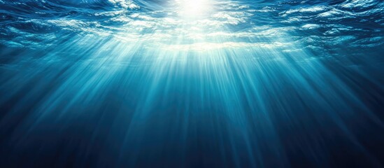 Poster - Aerial view of ocean surface illuminated by sunlight beams creating a serene and tranquil underwater atmosphere with space for text.