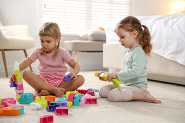 Canvas Print - Cute little sisters playing with colorful building blocks on floor at home