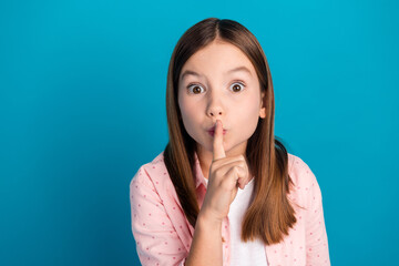 Wall Mural - Young girl making shushing gesture with finger to lips against blue background