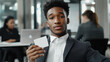 © Tossakan Photos - A young businessman in a suit sits confidently in his office, holding a bank business card, while coworkers work behind him. A perfect concept for finance, banking, and professionalism.