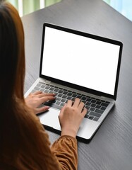 young woman using computer laptop in front of an blank white computer screen in home 