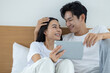 © Washburn - Happy couple watching movies and dramas on the bed