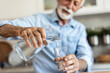 © Jelena Stanojkovic - Senior man pouring water from the jug into glass in the kitchen. Senior man drinking water.