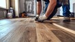 © Gophotograph - A close-up view of a man installing wood flooring in an empty room.