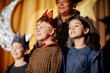 © Seventyfour - Three children wearing costumes standing on stage during school play in front of curtain. Smiling children in various costumes happily participating in event
