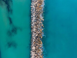 Poster - Aerial view of rocky breakwater in turquoise waters.