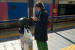 © Connect Images - Woman standing at train platform checking phone near luggage and backpacks. Kyoto, Japan
