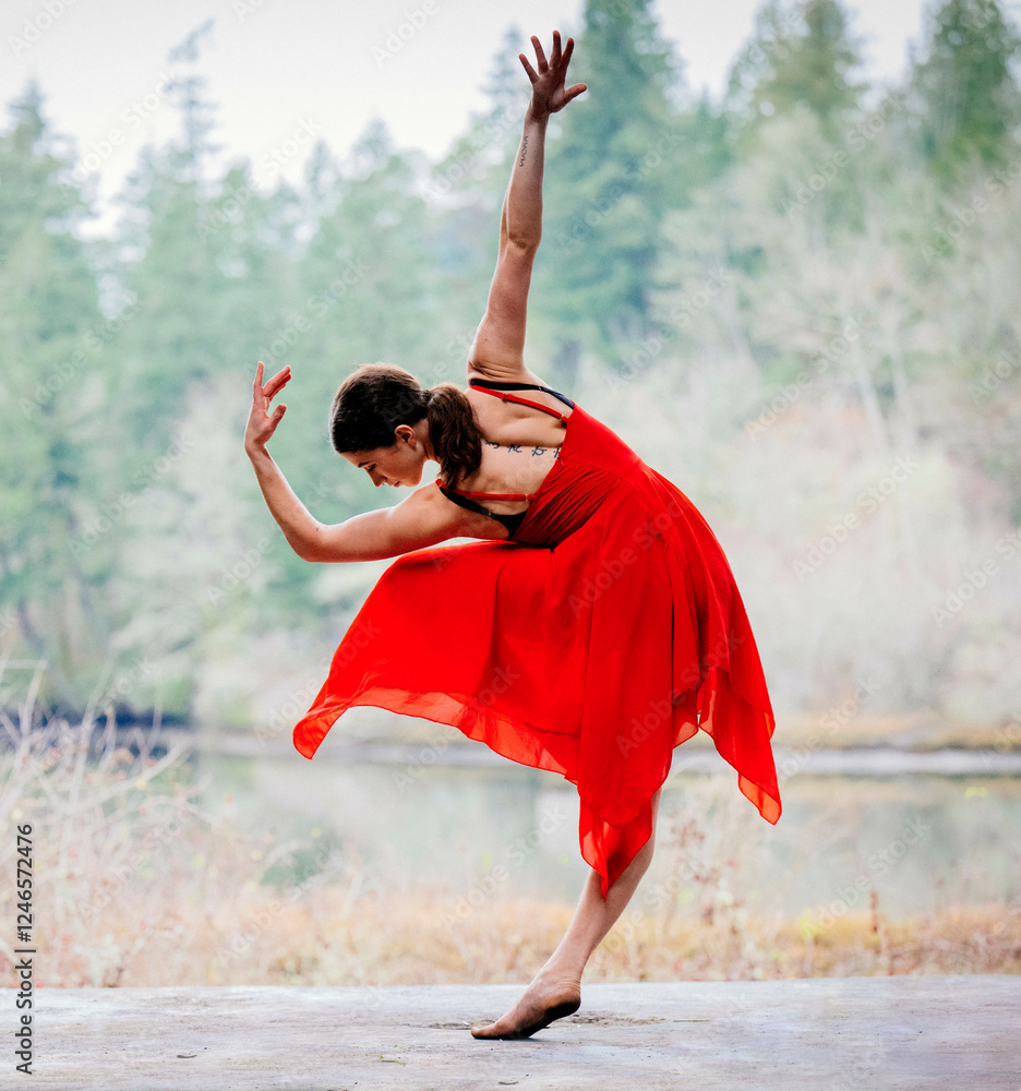 Dancer in a flowing red dress poses gracefully in front of a serene ...