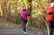 © Connect Images - Woman wearing a headscalf and man jogging together on a sunny wooded trail. Sale Water Park, Manchester, UK