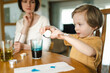 © MNStudio - Big sister and her little brother dyeing Easter eggs at home. Children painting colorful eggs for Easter hunt. Kids getting ready for Easter celebration.