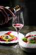 © pavel siamionov - A hand pours red wine into a glass, accentuating a gourmet dining experience. Stylish plates feature vibrant dishes, enhancing the elegance of the setting. Perfect for food and beverage themes.