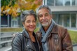 © Markus Schröder - Portrait of a content multicultural couple in their 60s sporting a classic leather jacket in front of modern university campus background