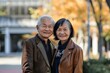 © Markus Schröder - Portrait of a grinning asian couple in their 60s sporting a stylish leather blazer isolated in modern university campus background