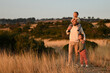 © Mariia Andreeva - Father walking with his daughter and son through fields at sunset. Warm golden light, family bonding, peaceful nature scene. Happy childhood memories, love, and togetherness.