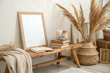 Sticker - A cozy interior scene featuring a bench with books, a blank frame, candles, and decorative plants, creating a warm and inviting atmosphere.