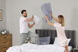 © New Africa - Couple having pillow fight while changing bed linens at home