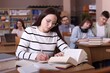 © New Africa - Beautiful woman reading book and taking notes at desk in public library
