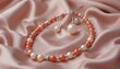 © Nata - Elegant pearl and coral necklace with matching earrings resting on satin fabric