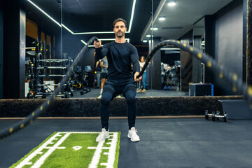 Muscular man working out with battle ropes.