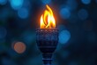 © Graph Squad - Glowing flame atop an ornate torch set against a blurred deep blue background creates an atmosphere of warmth and mystery