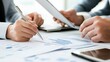 © Jaroon - Analyzing the Data: Close-up of hands reviewing financial documents, emphasizing collaboration and strategic decision-making. The image conveys professionalism and meticulousness.