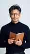 © Роман Варнава - Asian male writer adjusting glasses while reviewing manuscript in isolated studio setting