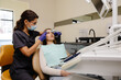 © nazariykarkhut - Female dentist trying on a facial arch for a patient sitting in a dental chair
