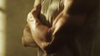 © Oleksandra - Close-up of muscular man's crossed arms in a sleeveless shirt showcasing strength and definition in warm natural lighting