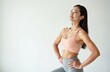 © Vadym - Fit Asian woman stands confidently in activewear. Posing for fitness photo shoot. Woman smiles, healthy physique. Indoor shot features white background. Image emphasizes toned upper body, slim waist,
