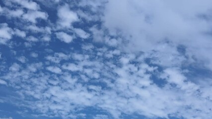 Wall Mural - White clouds in a bright blue sky textured background abstract